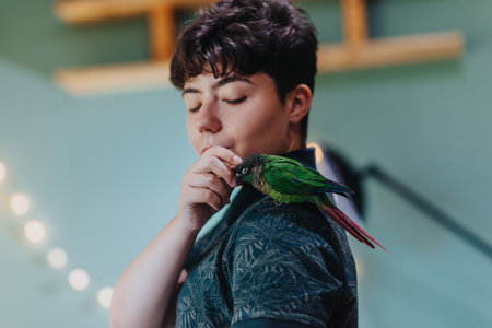 Young person gently interacting with vibrant green parrot indoorsの写真素材