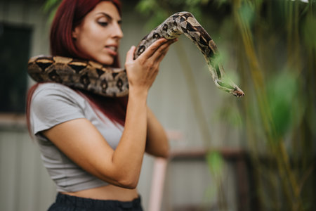 Girl gently holds a large snake outdoors in natural settingの写真素材