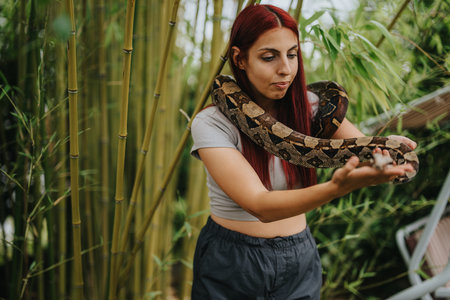 Girl holding a snake in a bamboo forest settingの写真素材