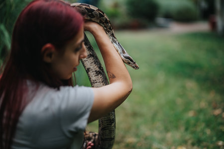 Girl interacting with snake in outdoor green settingの写真素材