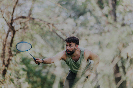 Young man playing badminton in a sunny park settingの写真素材