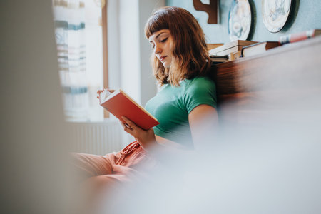 Young woman relaxing and reading a book at homeの写真素材