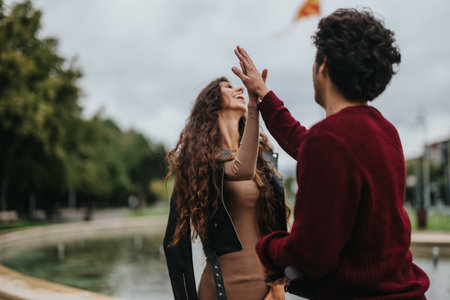 Joyful young couple sharing a high five in urban parkの写真素材