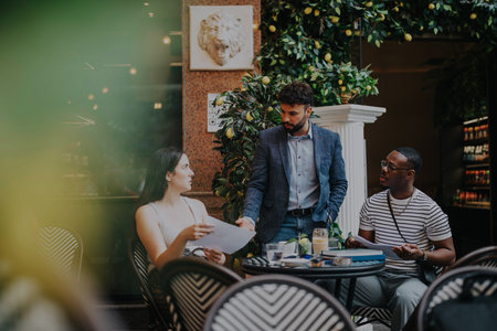 A diverse group of professionals discussing a project in a modern coffee shop.の写真素材