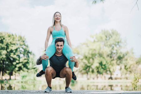 Two friends enjoying a sunny fitness session in the park showing strength and balance with a playful...