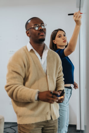 Two colleagues are actively brainstorming ideas during a project meeting. The setting is an office environment, fostering teamwork and creativity.の写真素材