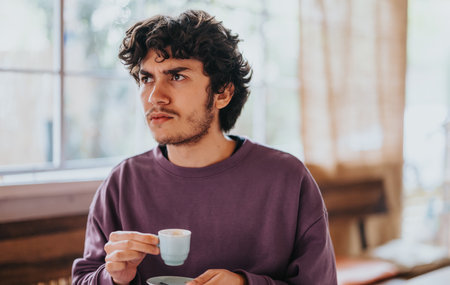 Pensive young man enjoying coffee in a cozy cafe