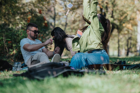 Friends enjoying a playful card game in the parkの写真素材