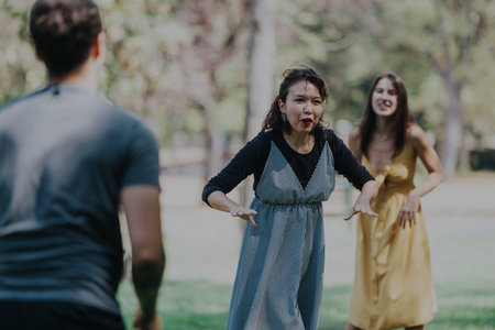A lively group of friends engages in playful activities in a sunny park setting, expressing joy and friendship.の写真素材