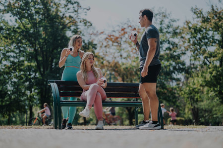 Friends enjoying casual gathering in sunny park settingの写真素材