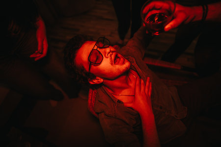 A joyful gathering of friends celebrating a birthday at home, enjoying drinks and laughter in a cozy, dimly lit environment.の写真素材