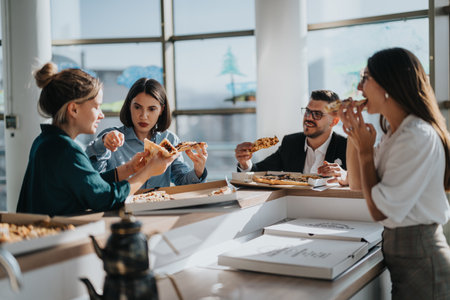 Business team enjoying a casual pizza lunch break discussionの写真素材
