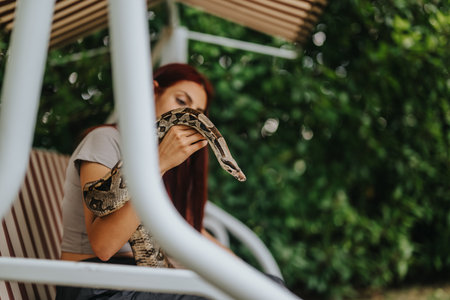 Girl interacting with a snake on a garden swing seat