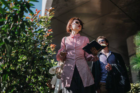 Confident business people walking outside in bright sunlightの写真素材