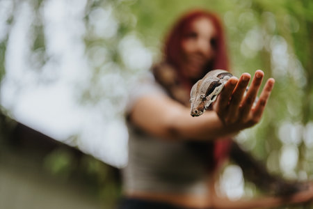 Girl holding a snake with blurred nature background