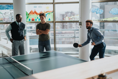 Business workers enjoying a ping pong game at the officeの写真素材