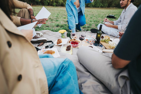 Group of friends enjoying an outdoor picnic with food and wineの写真素材