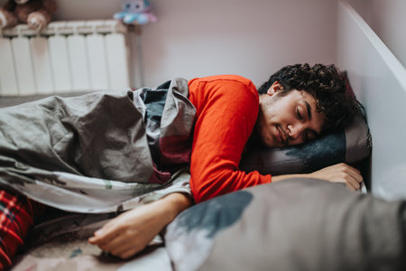 Young man sleeping peacefully in bed with cozy blanketの写真素材