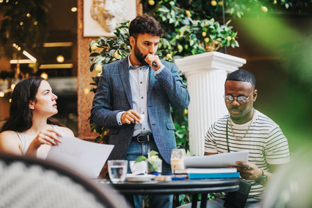 A diverse group of business professionals brainstorm and discuss project ideas in a stylish coffee bar.の写真素材