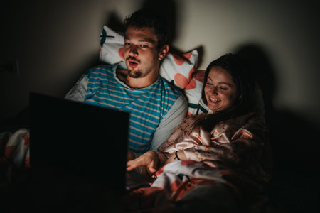 Couple enjoying late night movie on laptop in bed together