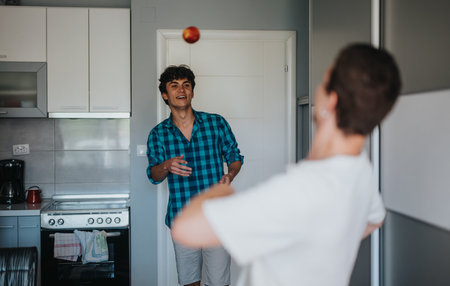 Friends having fun in the kitchen with an appleの写真素材