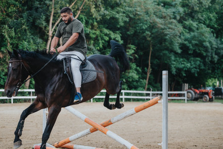 Man riding horse during equestrian jump training outdoors in arenaの写真素材