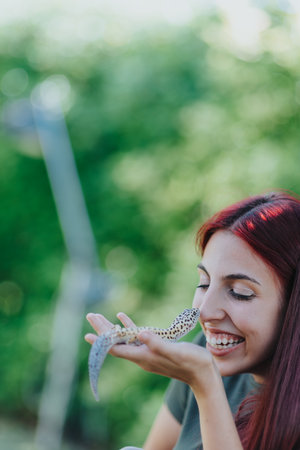 Joyful young girl happily playing with a pet lizard outdoors, enjoying nature with laughter and curiosity, creating a delightful connection with her reptile friend on a sunny day in the garden.の写真素材