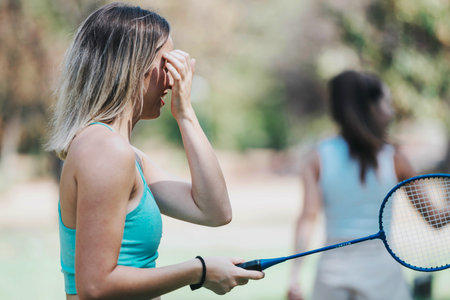 Two friends playing badminton in a sunny park settingの写真素材