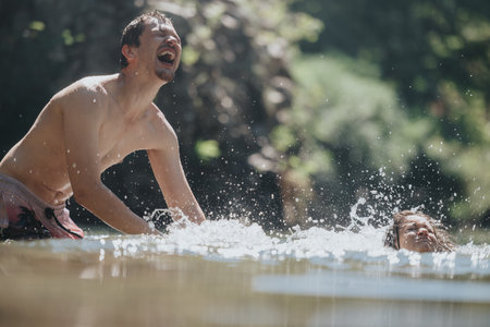 Father and child enjoying a playful swim in natural waterの写真素材
