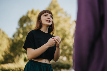 Young woman engaged in conversation outdoors on a sunny dayの写真素材
