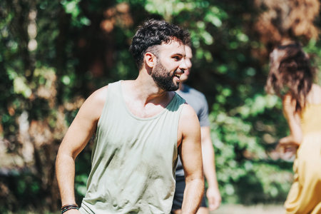 Young man enjoying a sunny day with friends in the park, wearing casual summer clothes and smiling...