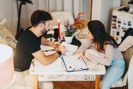 Focused college students studying at home together at a cozy tableの写真素材