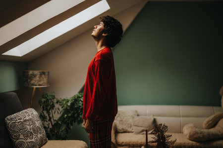 Man in red shirt standing in a cozy, modern living roomの写真素材