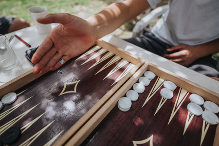Hand playing backgammon with dice on an outdoor tableの写真素材