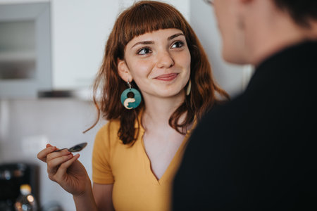 Woman in yellow top smiling and enjoying a conversation in kitchenの写真素材