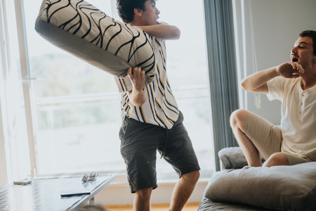 Friends having a playful pillow fight indoorsの写真素材