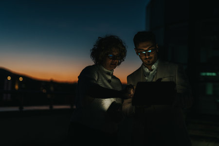 Multigenerational colleagues collaborating on a rooftop at sunset with tablet