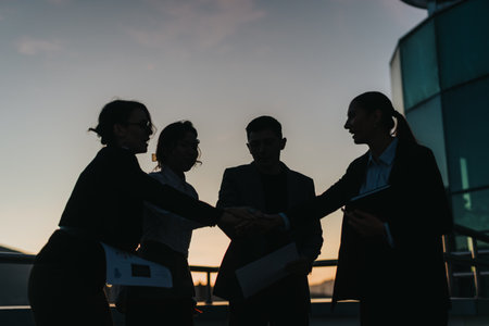 Silhouetted business people gather for a motivational meeting at sunset, highlighting teamwork and ambition.の写真素材