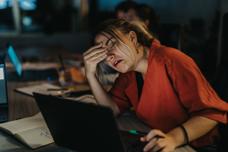 Stressed businesswoman working late at night in office setting