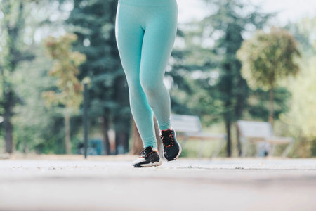 Woman jogging in the park wearing turquoise leggings on a sunny day