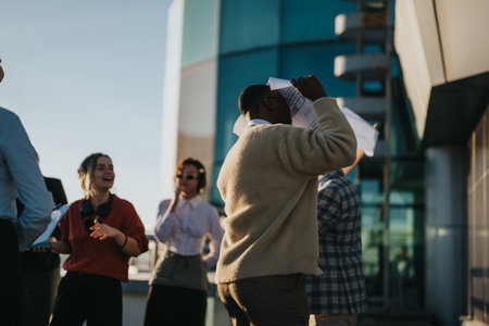 Diverse business team celebrating success on rooftop at sunsetの写真素材
