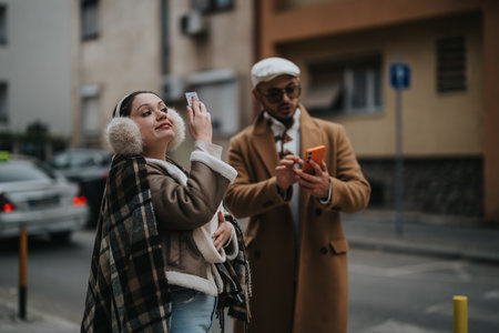 Young couple taking photos with smart phones on a city streetの写真素材