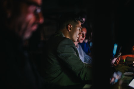 A team of multicultural colleagues working late at night, deeply focused on a collaborative project.の写真素材