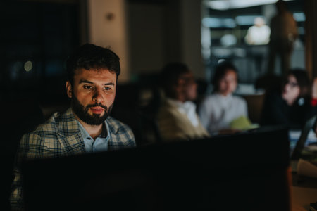 Focused businessman working late and collaborating with colleagues in officeの写真素材