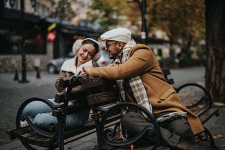 Happy couple sitting on a park bench during a crisp autumn dayの写真素材