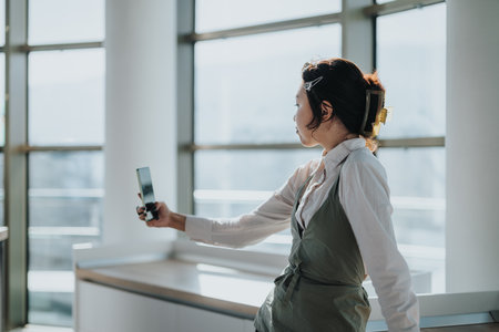 Businesswoman taking a break with a smart phone selfie in officeの写真素材