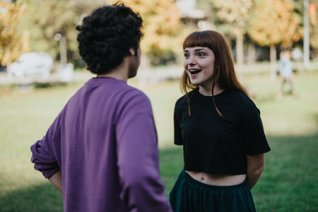 Young couple engaged in lively conversation outdoors in park settingの写真素材