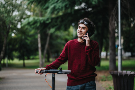 Young man talking on phone with electric scooter in parkの写真素材