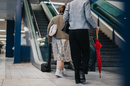 Two women walking up the stairs in a modern urban area holding accessories and shopping bagsの写真素材