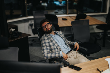Tired employee resting in a modern office late at nightの写真素材